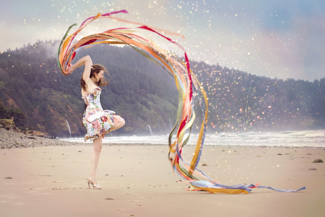 A woman dancing happily with ribbons on the beach